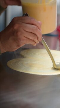 Street Vendor Spreading Batter on Hot Metal Griddle for Crepes