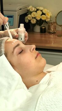 Cosmetician applies facial serum to a teenage girl's skin in a beauty clinic, professional skincare, hydration, gentle cosmetic care, healthy complexion.
