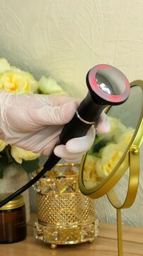 Close up front view of a cosmetic device applicator held in a gloved hand, professional beauty equipment, skincare technology, salon presentation.