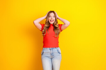 Fototapeta premium Happy surprised young woman in red shirt and jeans on bright yellow background expressing joy and excitement