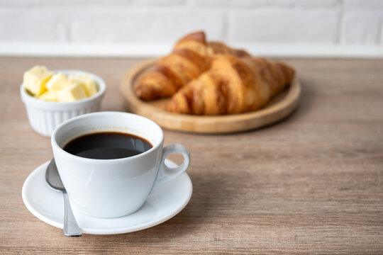 Black coffee with fresh croissants on wooden table. Copy space