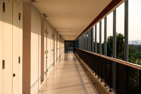 Empty Corridor Hallway With Open Balcony Railing and Warm Sunset Light in Building