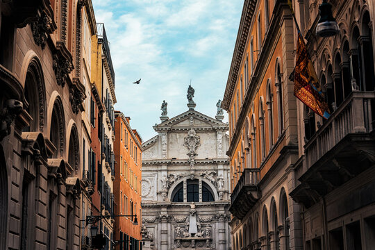 Baroque Church Facade Framed by Classic Buildings in Narrow Street in Venice Italy
