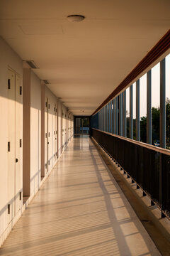 Empty Corridor Hallway With Open Balcony Railing and Warm Sunset Light in Building