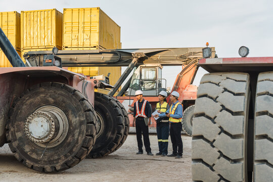 Team Worker Inspecting and Discussing About Reach Stacker Heavy Machinery at Industrial Container Yard