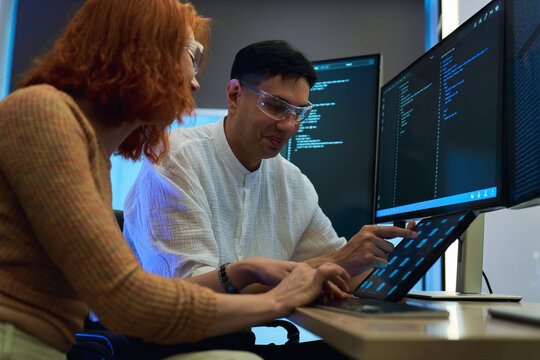 A professional male and female software developer working together on a complex programming project