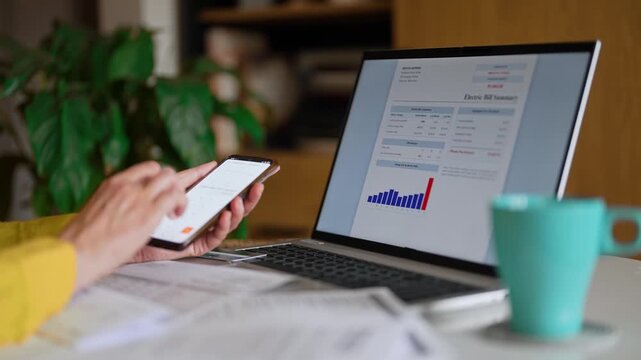 Woman calculating utility bills and household expenses on smartphone calculator.