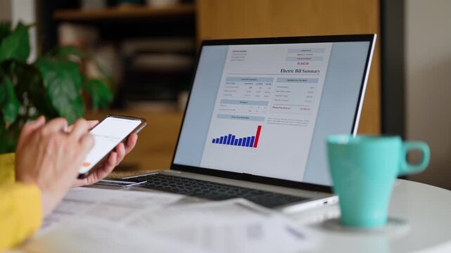 Woman calculating utility bills and household expenses on smartphone calculator.