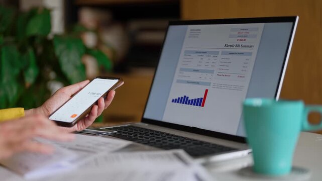 Woman calculating utility bills and household expenses on smartphone calculator.
