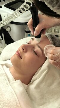 Teenage girl receives a vacuum hydropeeling facial treatment in a beauty clinic, professional skincare, pore cleansing, gentle exfoliation, healthy skin.