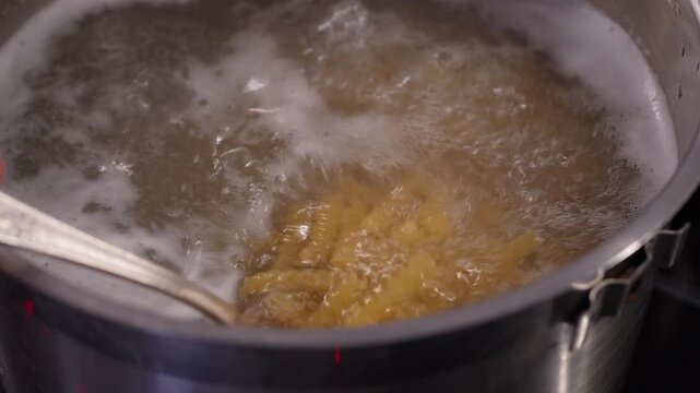 4K slow-motion video of boiling and stirring fusilli pasta in a pot