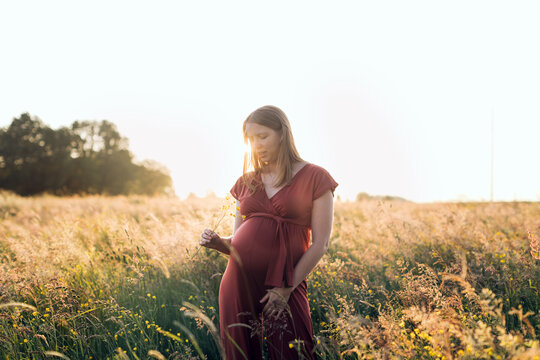Pregnant woman enjoying nature during sunset golden hour