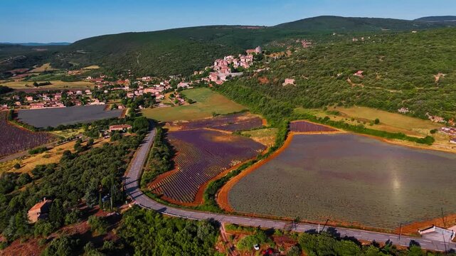 Aerial drone view Simiane-la-Rotonde among the mountains and blooming purple lavender fields. Provence-Alpes-Cote d'Azur region. High quality 4k footage