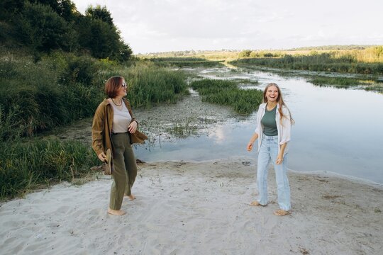 Two happy women enjoying friendship standing by river