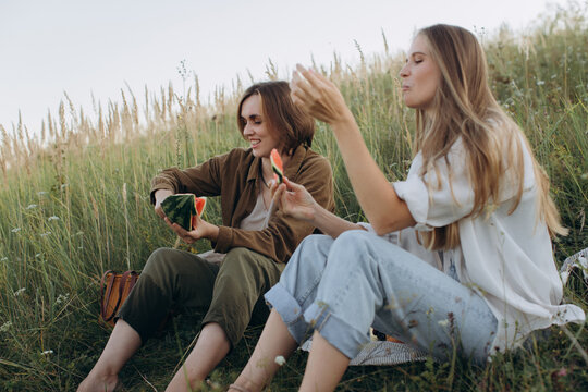 Friends enjoying picnic sharing watermelon outdoors