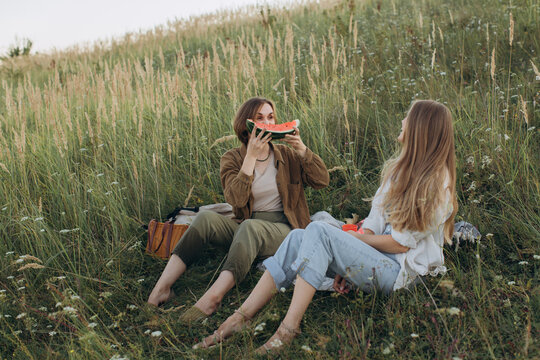 Women friends enjoying outdoor picnic eating watermelon