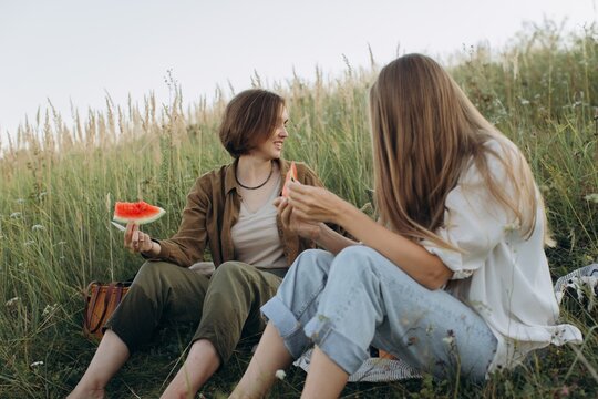 Friends sharing watermelon outdoors in natural field