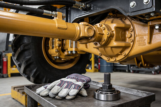 Heavy machinery drivetrain components and work gloves on a metal tray