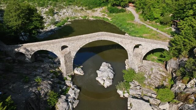 Devils Bridge aerial top view of historic stone arch bridge over Arda River in Rhodope Mountains Bulgaria drone footage summer travel destination landmark
