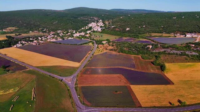 Aerial drone view Simiane-la-Rotonde among the mountains and blooming purple lavender fields. Provence-Alpes-Cote d'Azur region. High quality 4k footage