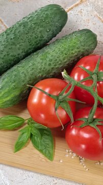 Concombres tomates basilic sur une planche en cuisine	