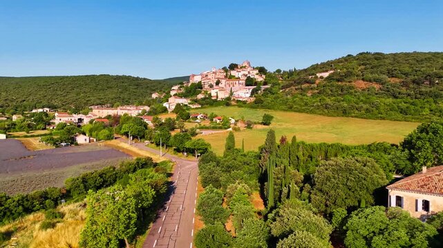 Aerial drone view Simiane-la-Rotonde among the mountains and blooming purple lavender fields. Provence-Alpes-Cote d'Azur region. High quality 4k footage
