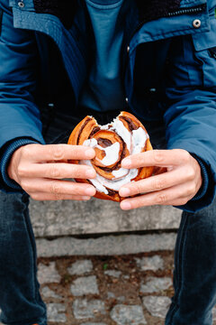 a man holding a bitten danish kanelsnegl on steps