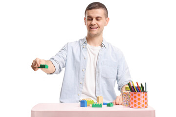 Fototapeta premium Young man playing with building blocks at a table