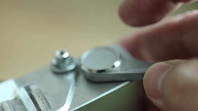 Horizontal 4K close up footage of a man hand operating a metal film advance lever then pressing shutter release button on classic analog camera