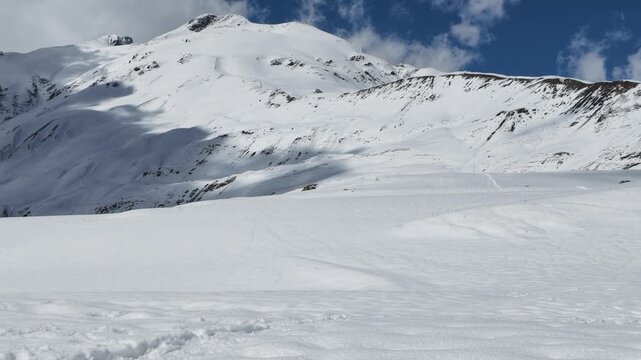 Snowy Koruldi ridge landscape in Svaneti Georgia, high altitude mountain peak under blue sky with clouds