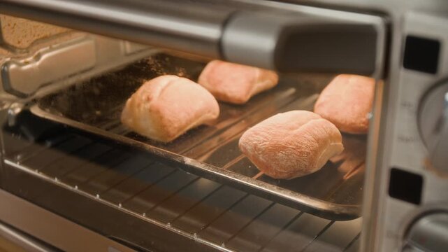 Bread rolls baking and rising inside toaster oven in time lapse. Clip for kitchen appliance promotions, cooking shows, and culinary school advertisements
