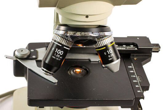 Close-up of interchangeable microscope objective lenses positioned above the mechanical stage. Professional laboratory optics for biological and medical research.