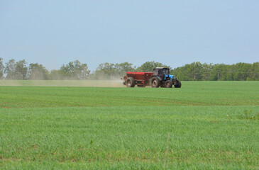 Obraz premium Tractor Spreading Fertilizer in Agricultural Field front view