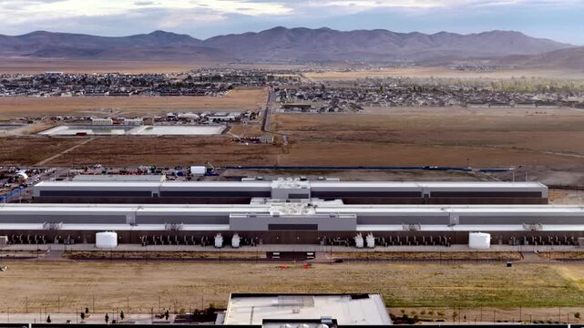 Aerial flyover of a Data Center, revealing sprawling facilities, distant Utah town of Eagle Mountain, and dramatic mountain backdrop under soft, natural morning light.