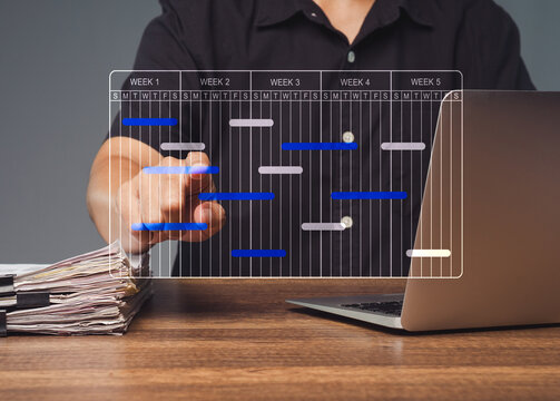 Person managing digital project timeline beside laptop