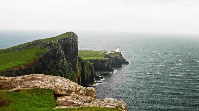 Majestic view of neist point lighthouse standing on dramatic cliffs overlooking the choppy sea. Famous scottish landmark on the isle of skye