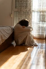 Sad lonely female feeling down, sitting on bedroom floor wrapped in bedsheet. Apathy, grief and despair. © olezzo