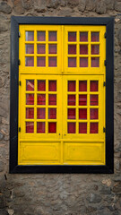 Obraz premium Lanzarote architecture and vibrant colors traditional yellow window with red shutters on a rustic stone wall in the Canary Islands Spain