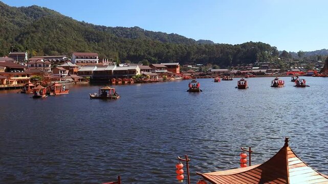The video of Baan Rak Thai captures traditional Chinese-style boats floating on a tranquil lake, surrounded by mist-shrouded mountains and charming architecture reminiscent of Chinese settlements. It'