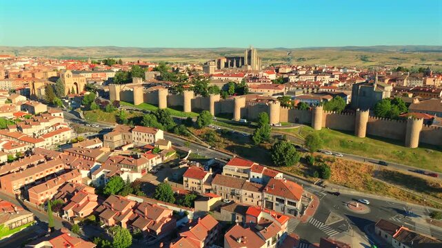 A drone glides low along the ancient stone walls of Avila, Spain, tracing red rooftops beyond.
