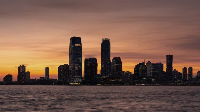 Jersey City skyline timelapse from sunset to twilight with Exchange Place skyscrapers and Hudson River waterfront. New Jersey, USA