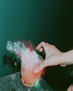 Frozen splash of a pink cocktail in a hand over a dark slate surface for premium beverage branding and hospitality advertisements