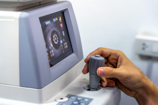 Unrecognized professional eye doctor fine-tuning optical instruments for accurate eyesight testing, refraction assessment, and prescription glasses fitting in modern optical shop