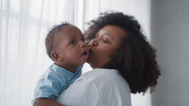 Portrait of cute little boy in hand of mother in cozy home interior, slow motion . Motherhood and childhood, pretty infant child looking around, exploring world, curious baby and happy mother at home
