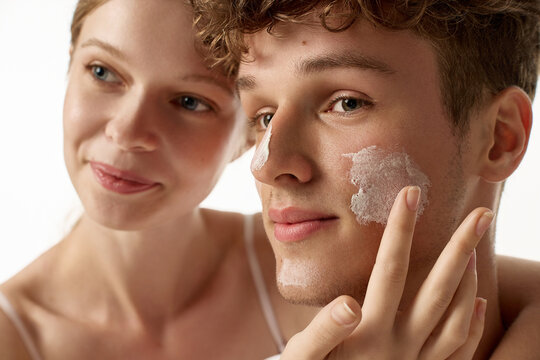 Extreme close-up of curly-haired young man showing thick sunscreen texture. Concept of visible sunscreen texture, no white cast concept, men's summer skincare.