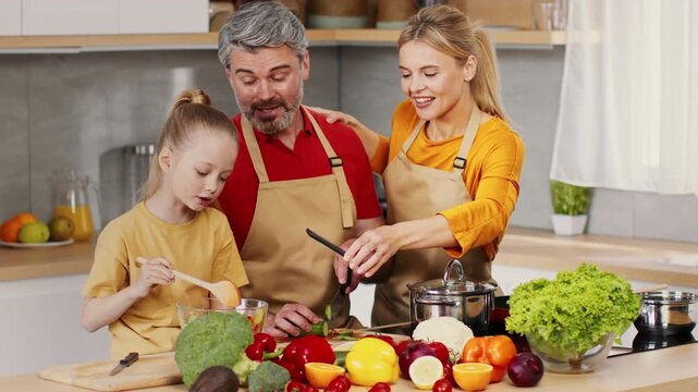 Joyful Family Group Featuring Middle-aged Man, Young Girl, And Adult Woman Engaging In Cooking Process Together In Modern Kitchen, Making Healthy Meal With Fresh Ingredients. Weight Loss Concept.