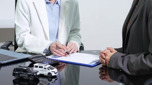 Asian woman uses a calculator to estimate car loan monthly payment, planning budget, finance, credit, and vehicle insurance.