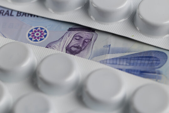 UAE dirham banknote visible between medicine blister packs representing healthcare costs in Emirates