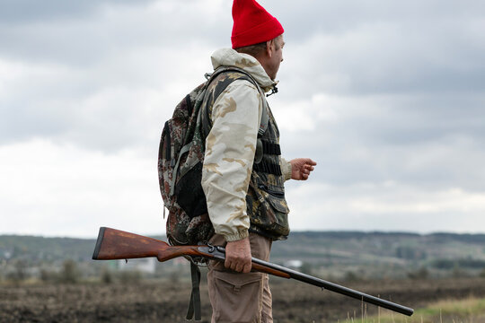 A hunter with a gun in camouflage clothing. A gentleman with a gun, medium shot, unrecognizable.