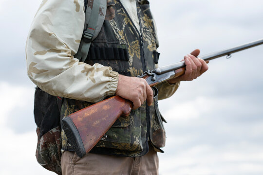 Close-up of a hunter's hand with a gun. Medium shot of a hunter with a weapon.
